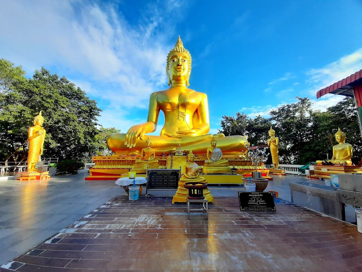 Ornate white and gold chedi stupa at Wat Yansangwararam temple complex near Pattaya, reflected in a lotus pond