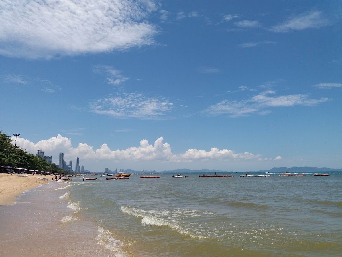 Jomtien Beach on a clear day with calm water, open sand and the Pattaya skyline visible in the distance