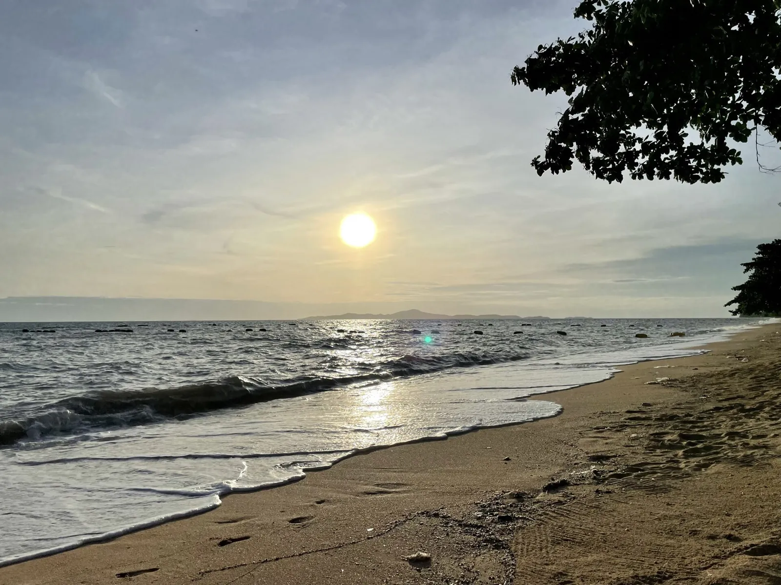 Jomtien Beach at sunset with a pier and the sun low over the sea