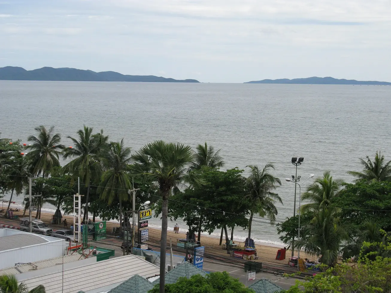 Beach chairs and umbrellas on Jomtien Beach with people in the shallows
