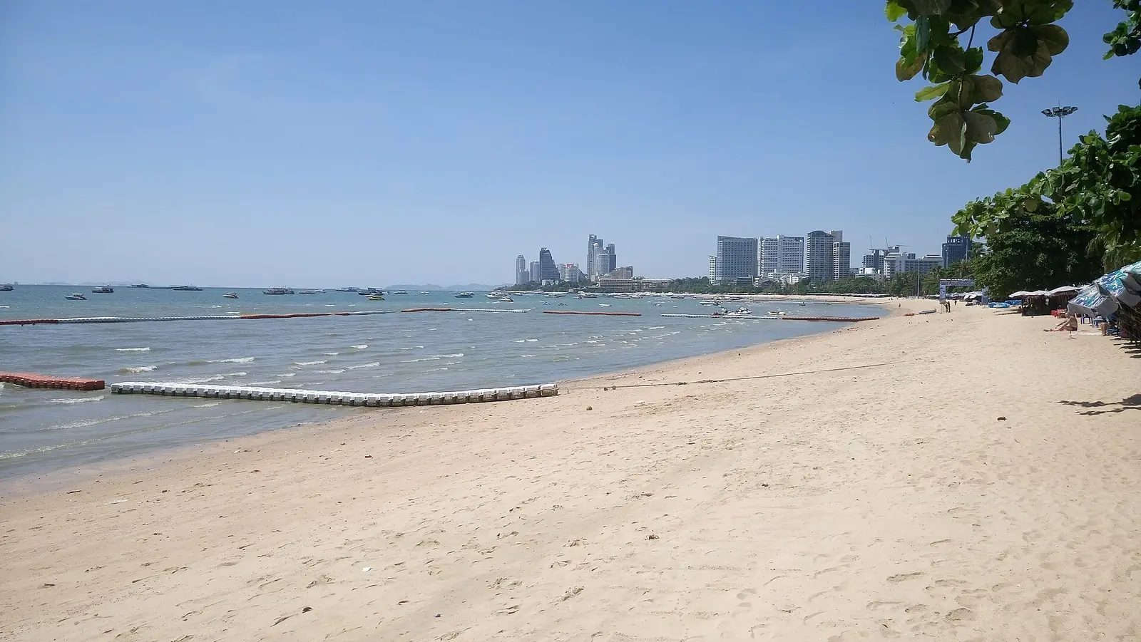 Pattaya Beach on a sunny June day, with umbrellas along the sand and the bay in front of the hotels