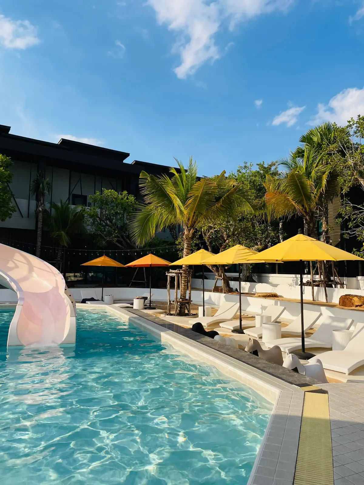 A sunny resort pool in Pattaya with loungers and palms