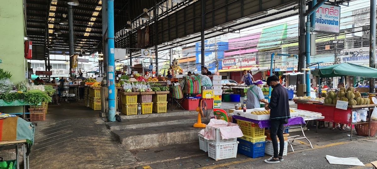 Naklua market, Pattaya — a covered fresh market with colourful fruit and vegetable stalls, vendors and shoppers in a quiet, local atmosphere