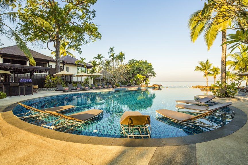 Infinity pool at Sea Sand Sun Resort Pattaya with sun loungers, palm trees and views over the Gulf of Thailand at sunset