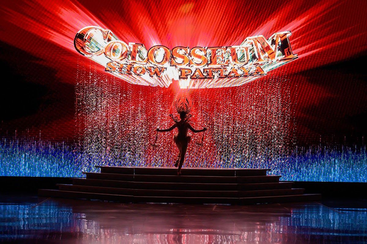 Performers on a theatre stage in elaborate colourful costumes under bright spotlights